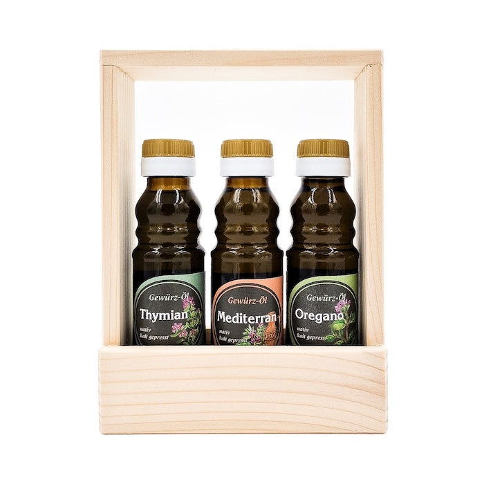 Geschenkset Kräuterlinge kaltgepresst nativ mit 100 ml Flasche Thymian Kräuteröl, 100 ml Flasche Mediterranes Gewürzöl und 100 ml Oregano Gewürzöl in einem Holztragerl auf weißem Hintergrund