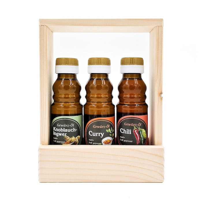 Geschenkset Würzlinge kaltgepresst nativ mit 100ml Flasche Knoblauch-Ingwer Gewürzöl, 100 ml Flasche Curry Gewürzöl und 100 ml Chili Gewürzöl im Holztragerl auf weißem Hintergrund