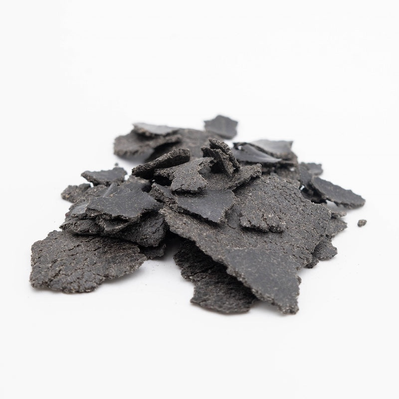 Schwarzkümmel Flakes schwarz als Futtermittel auf weißem Hintergrund