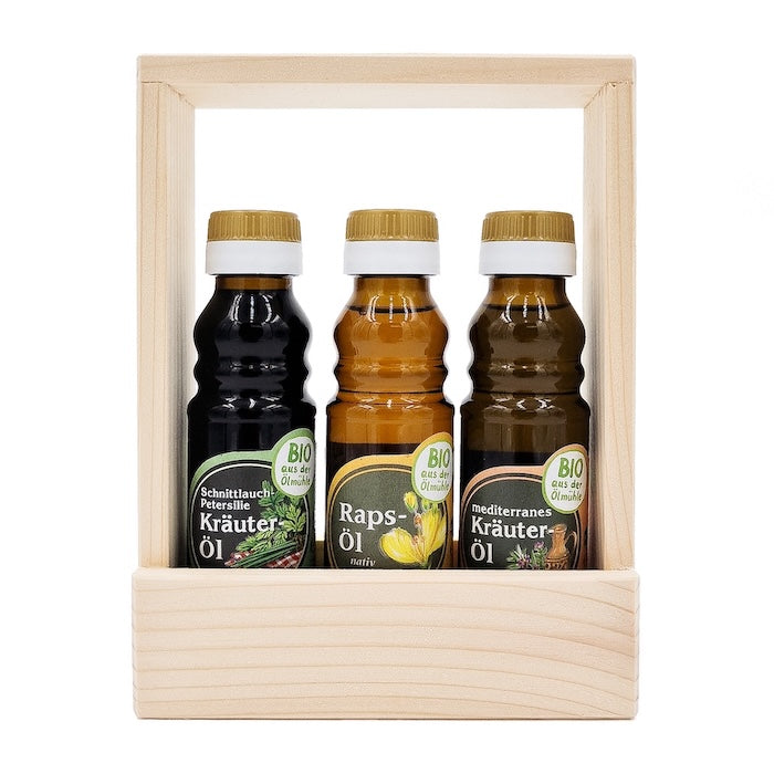 Geschenkset Bio Küche mit 100ml Flasche Bio Schnittlauch-Petersilie Kräuteröl, 100 ml Flasche Bio Rapsöl und 100 ml Flasche Bio mediterranes Kräuteröl in einem Holztragerl auf weißem Hintergrund