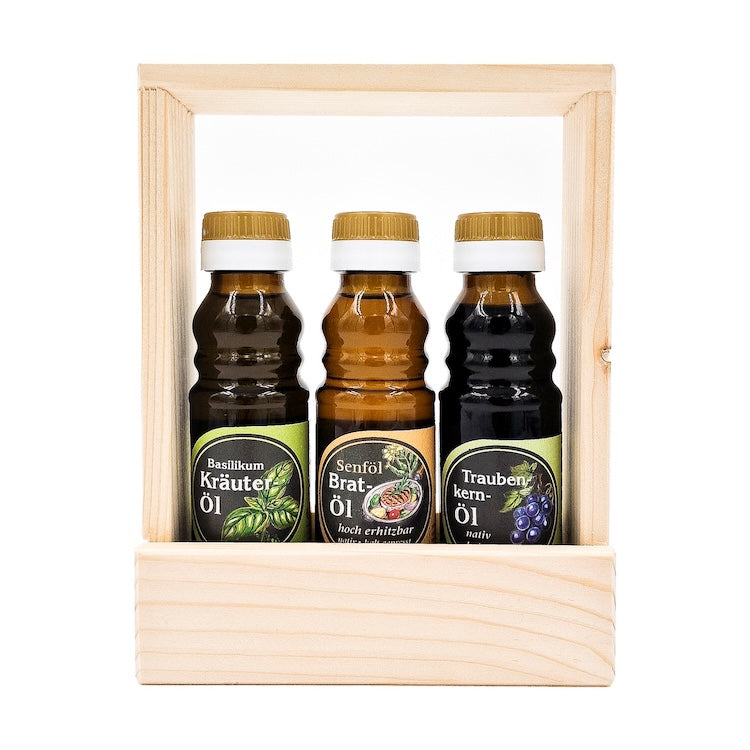 Geschenkset Kochprofi mit 100ml Flasche Senföl Bratöl hocherhitzbar, 100 ml Flasche Basilikum Kräuteröl und 100 ml Traubenkernöl in einem Holztragerl auf weißem Hintergrund