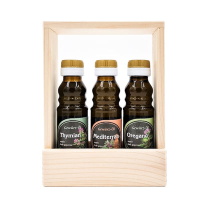 Geschenkset Kräuterlinge kaltgepresst nativ mit 100 ml Flasche Thymian Kräuteröl, 100 ml Flasche Mediterranes Gewürzöl und 100 ml Oregano Gewürzöl in einem Holztragerl auf weißem Hintergrund