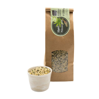 Hanfnüsschen, geschälte Hanfsamen vegan und glutenfrei, 250g Tüte braun der Ölmühle Garting mit hellgrünem Etikett auf weißem Hintergrund, im Vordergrund weiße Schale mit Hanfnüsschen