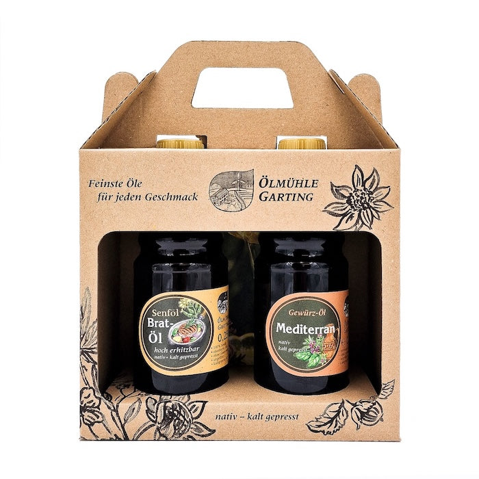 Geschenkset Küchenhelfer mit 250ml Flasche Senföl Bratöl hocherhitzbar, und 250 ml Flasche Gewürzöl Mediterran in Kartontasche auf weißem Hintergrund