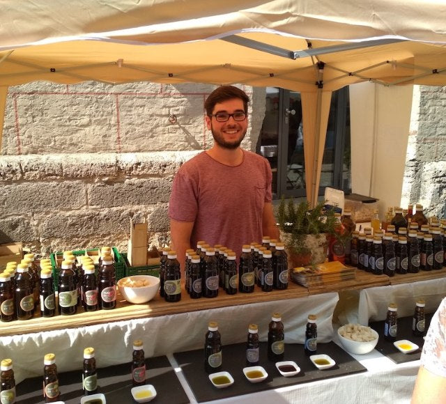 Mitarbeiter der Ölmühle Garting am Marktstand mit verschiedenen kaltgepressten Ölen und Verkostungsschälchen.